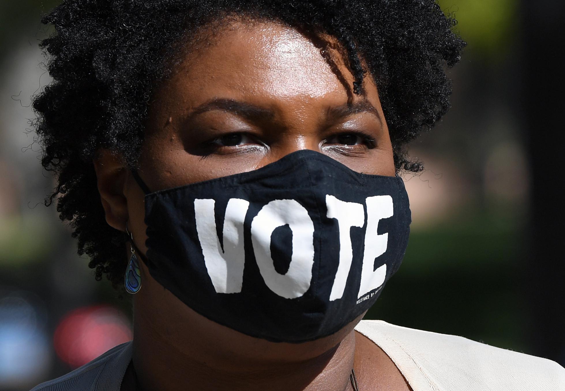 Stacey Abrams wears a face mask with the word Vote on it.