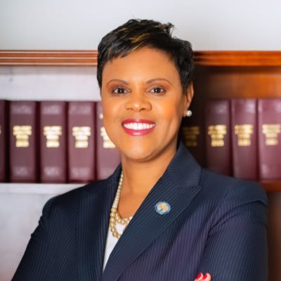 Shavonda Sumter in a navy blue blazer in front of books