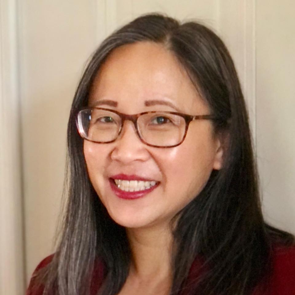 Laura Zhang Choi in black glasses in front of an off-white background