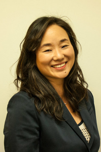 Jannie Chung in a black blazer in front of a yellow background