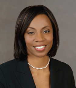 Angela Garretson in front of a gray background in a black blazer