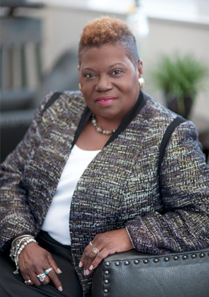 Jeannine sitting on a couch in a white and gray blazer