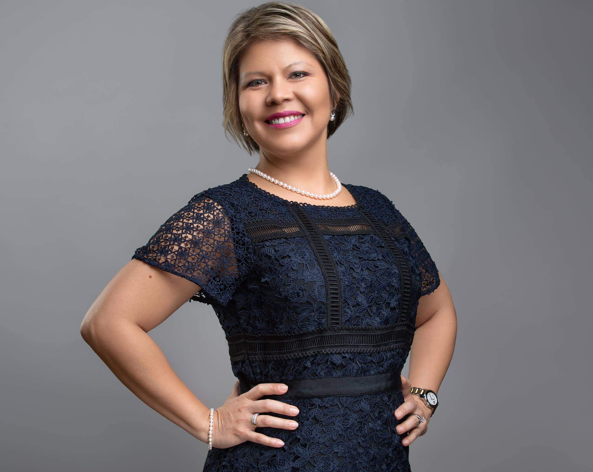 Dr. Patricia Campos-Media in a navy blue dress in front of a gray backgorund