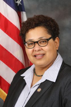 Rebecca Williams in a black blazer in front of an american flag