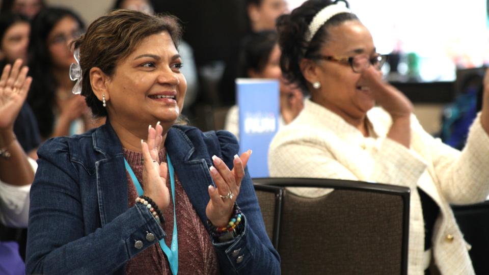 Two women seated, clapping 