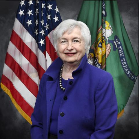 Janet Yellen in front of the american flag in blue jacket