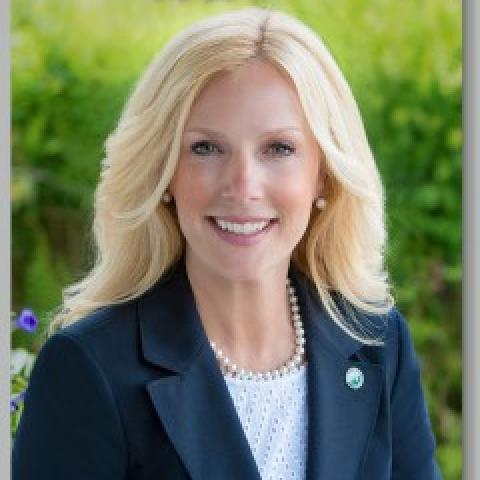 Christine Hanlon wearing navy blue suit against green background