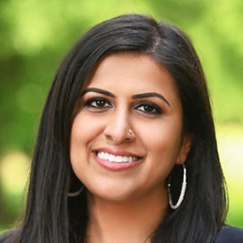 Head shot of Assemblywoman Sadaf Jaffer wearing white blouse and black jacket against a green leafy background