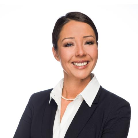 Head shot of Sheena Collum wearing a black jacket, white shirt and white necklace with hair pulled back