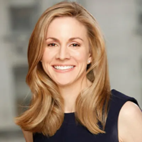 Head shot of Stacy Schuster wearing navy tank top against a gray background