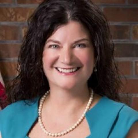 Bev Koehler wearing a blue blouse and white pearl necklace