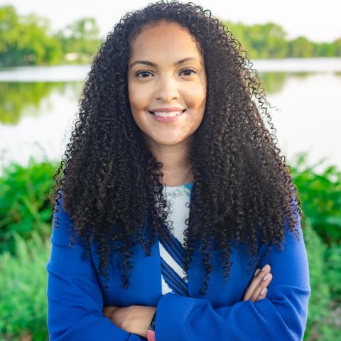 Headshot of Danielle Gee in a blue suit posing near the water 