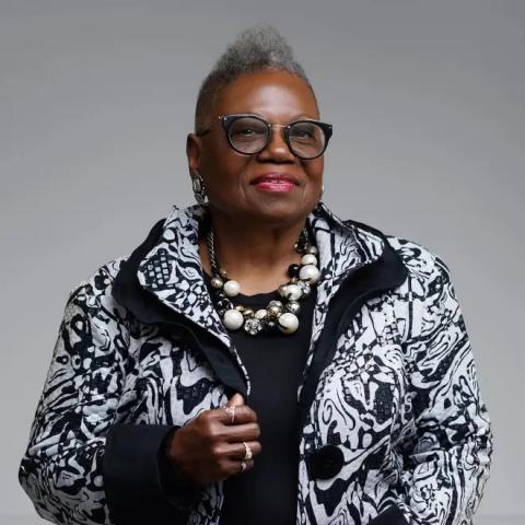 Jeanine LaRue wearing a black and white patterned blazer against a plain grey backdrop