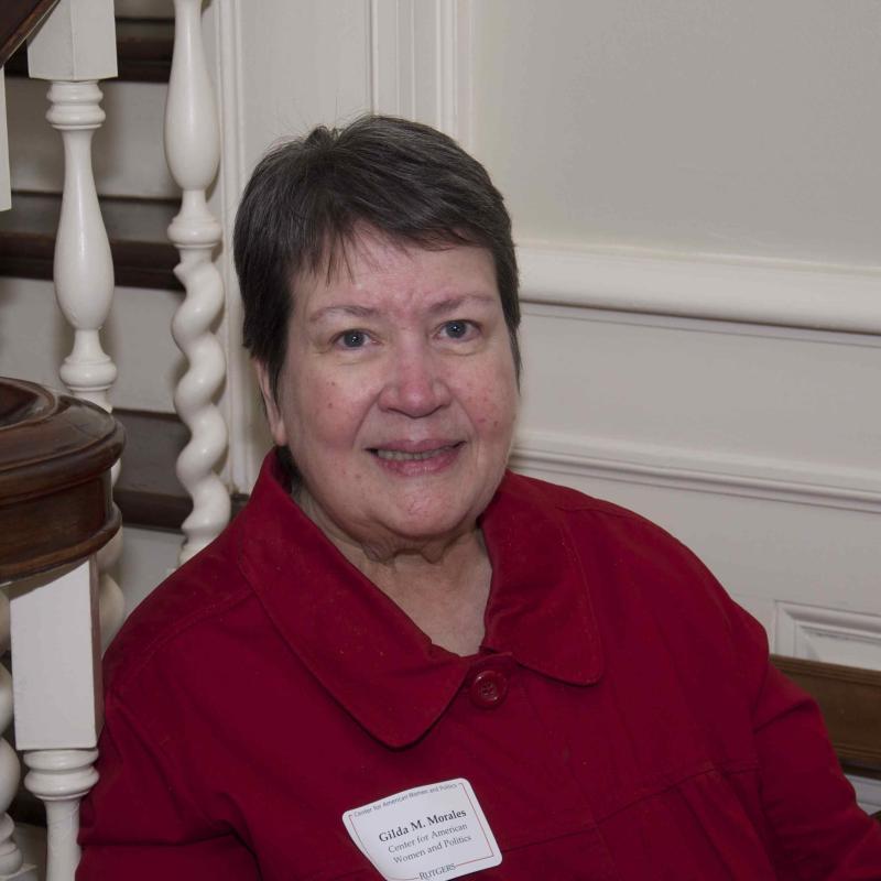 Head shot of Gilda Morales with short brown hair wearing a red jacket