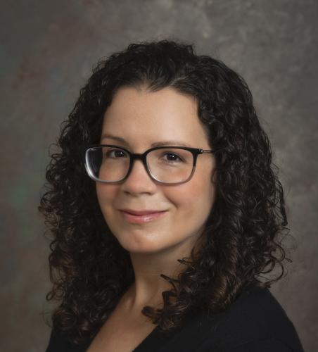 Erin Cassese in a black blouse in front of a gray background