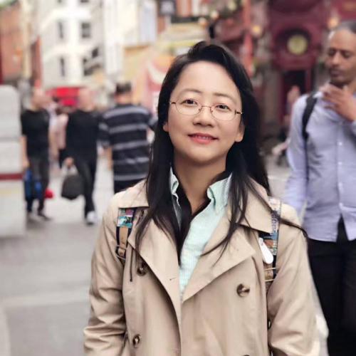 Dan Qi standing on a street with a beige trenchcoat