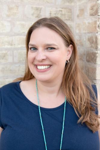 Heather Ondercin in a blue blouse in front of a white brick wall