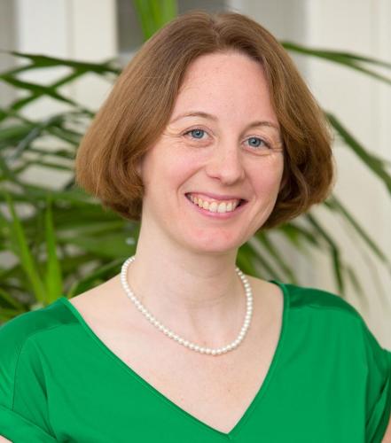 Anna Mahoney in a green shirt in front of a plant