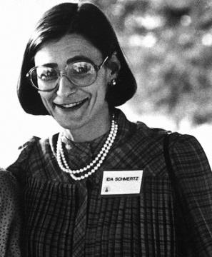 A younger Ida wearing glasses, pearls, and name tag that says Ida Schmertz