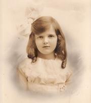 Katherine as a young girl wearing a dress and bow in her hair
