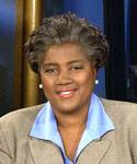 Donna Brazile wearing beige suit jacket and light blue collared shirt on set