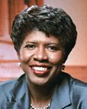 Gwen Ifill smiling wearing green shiny suit jacket on set