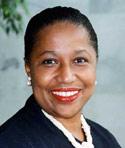 Carol Moseley Braun smiling outside wearing black suit jacket and white necklace