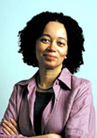 Patricia J. Williams posing with arms crossed in front of light blue background wearing light purple collared shirt