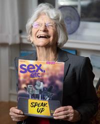 Susan Wilson laughing while holding up sex etc. magazine