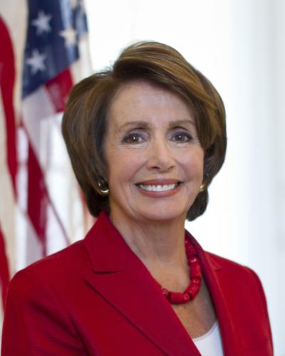 Representative Nancy Pelosi, wearing red suit with American flag behind her