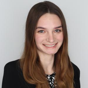 Samantha Koprowski in blazer smiling in front of neutal background