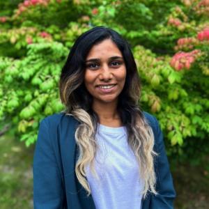 Asha Venugopalan in blue blouse and blazer in front of green background