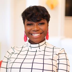 Karra McCray Gibson Smiling in front of blurred background wearing white patterned blouse