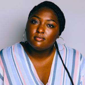 India Lenear in patterned blouse in front of neutral background