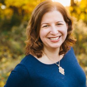 Heather Silber Mohamed in front of a blurred outdoor background in a blue blouse