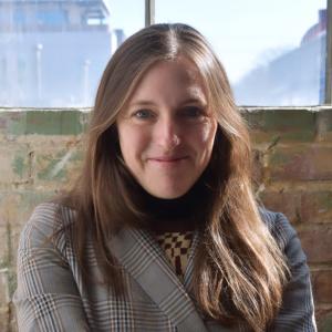 Alex Snipes in patterned blazer smiling in front of brick background