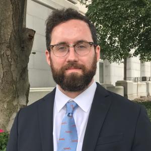 Paul Testa in a dark gray suit in front of a building.