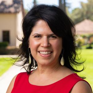 Anna Sampaio in a red top standing outside with a blurred background