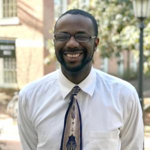 Chris Clark in a white shirt with a tie in front of a blurred background