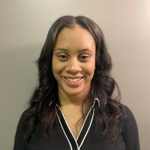 Sydney Carr in a black shirt in front of a beige wall