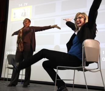 Chris Jahnke seated with arms raised in air, next to woman standing with arms in air