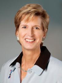 Christine Todd Whitman smiles in light blue jacket with black collar