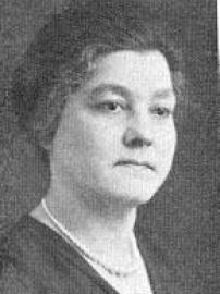 Head shot of woman with dark hair, pearl necklace, and black shirt